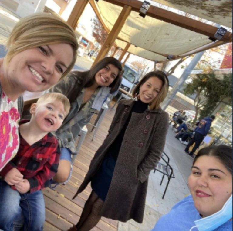 group smiling under awning on sidewalk corridor